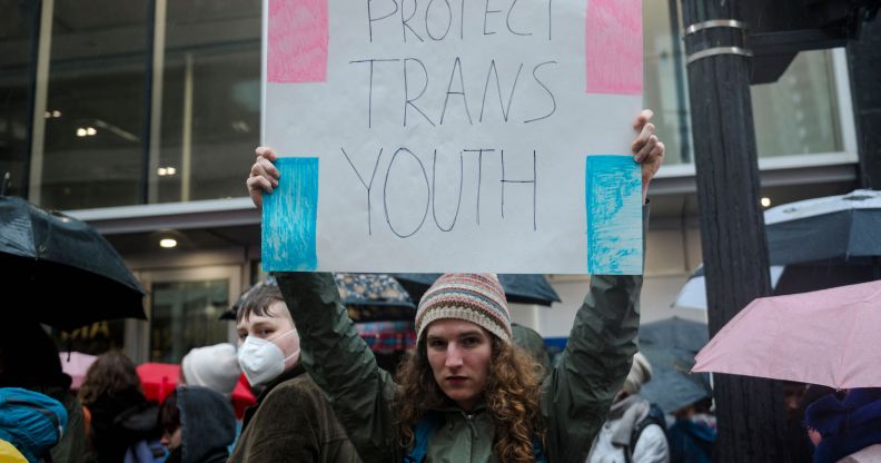 Man holds sign reading "protecting trans youth"