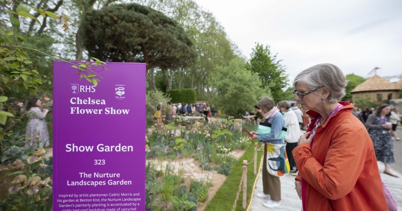 Woman seen looking at flowers next to a Chelsea Flower Show sign