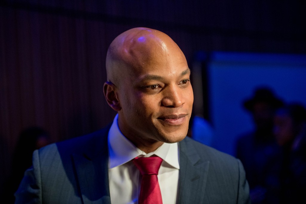 Maryland governor Wes Moore wearing a red tie and dark blue suit on a dark blue background