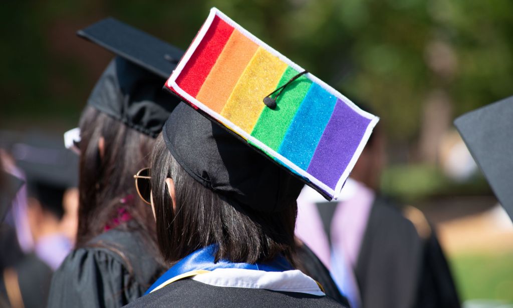 A picture of a person during graduation with a rainbow flag on their cap.