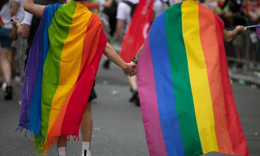 Two children wearing pride flags