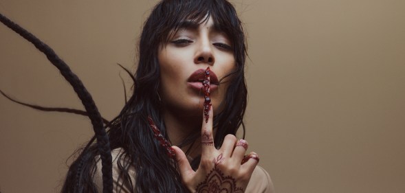 Sweden's Eurovision Song Contest 2023 winner Loreen wearing a cream top and placing a finger over her lips in a promotional photo for her Tattoo Uk and Europe Tour