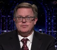 The Good Trouble Show presenter Matt Ford wears a suit and tie against a dark background