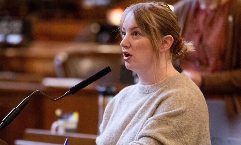 A picture of Megan Hunt speaking at her podium in the Nebraska state capitol.