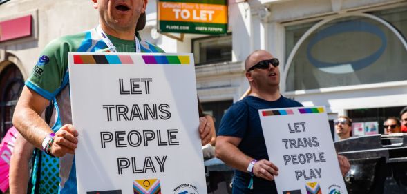 Groups of protestors hold signs reading "let trans people play" during a Pride event.