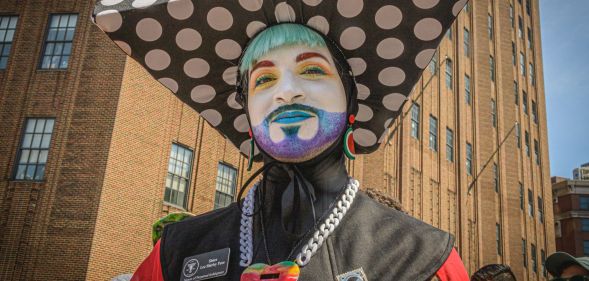 A member of the Sisters of Perpetual Indulgence, wearing an extravagant nun-style costume, glitter beard, and white face paint.
