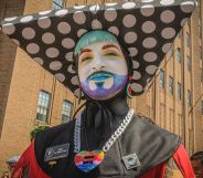 A member of the Sisters of Perpetual Indulgence, wearing an extravagant nun-style costume, glitter beard, and white face paint.