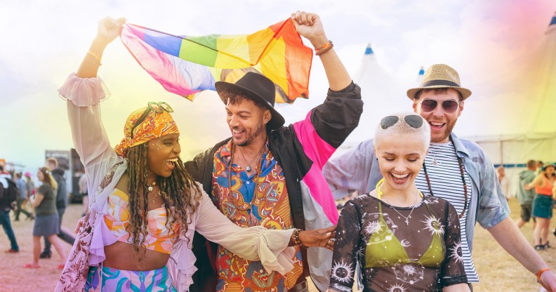 A group of friends at a music festival holding a rainbow Pride flag above their heads