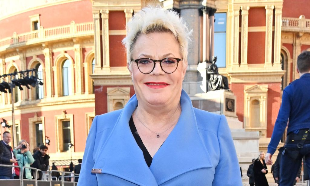 Suzy Izzard wears a blue coat as she stands outside and poses for photos at the 2023 Olivier awards.