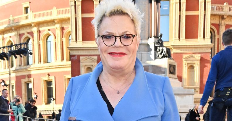 Suzy Izzard wears a blue coat as she stands outside and poses for photos at the 2023 Olivier awards.