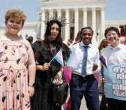 A group of four transgender youth smiling in a photo, with one of them holding a sign that reads "trans kids have always existed."