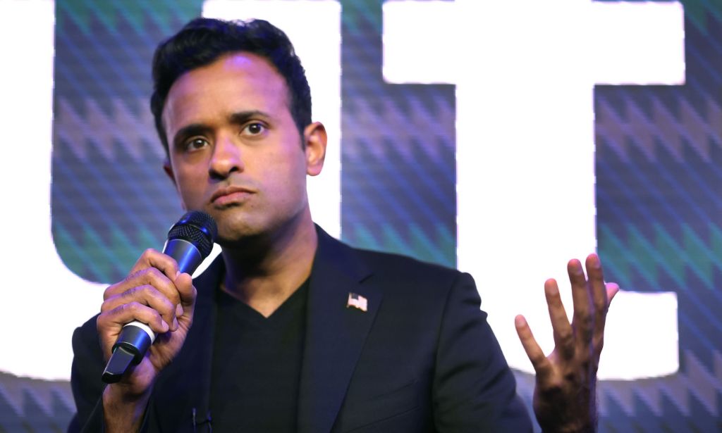 Entrepreneur Vivek Ramaswamy, who is a 2024 Republican presidential candidate, wears a dark shirt and jacket as he speaks into a microphone