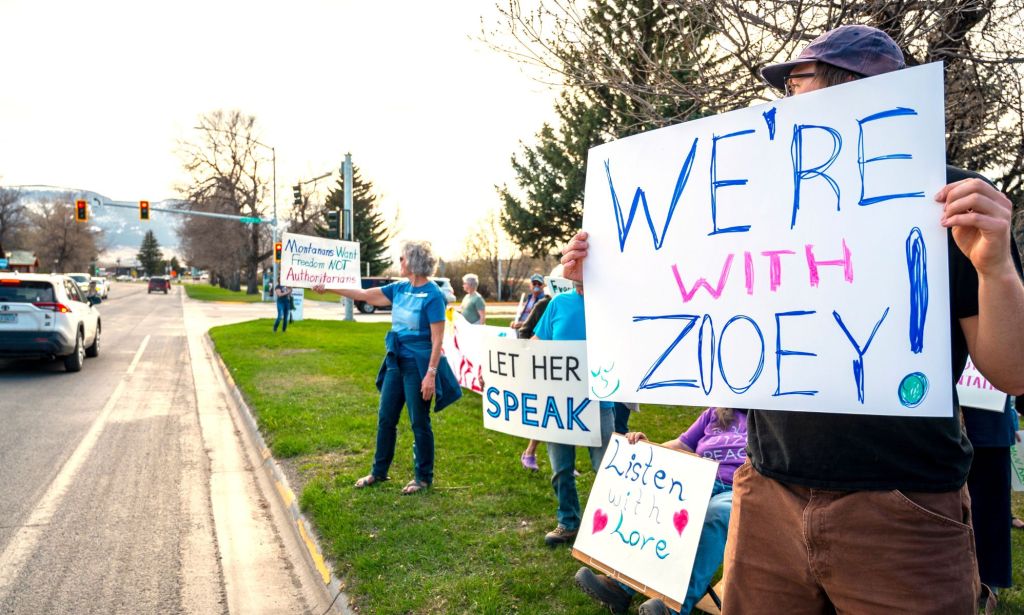 Protestors hold signs reading "we're with Zooey"