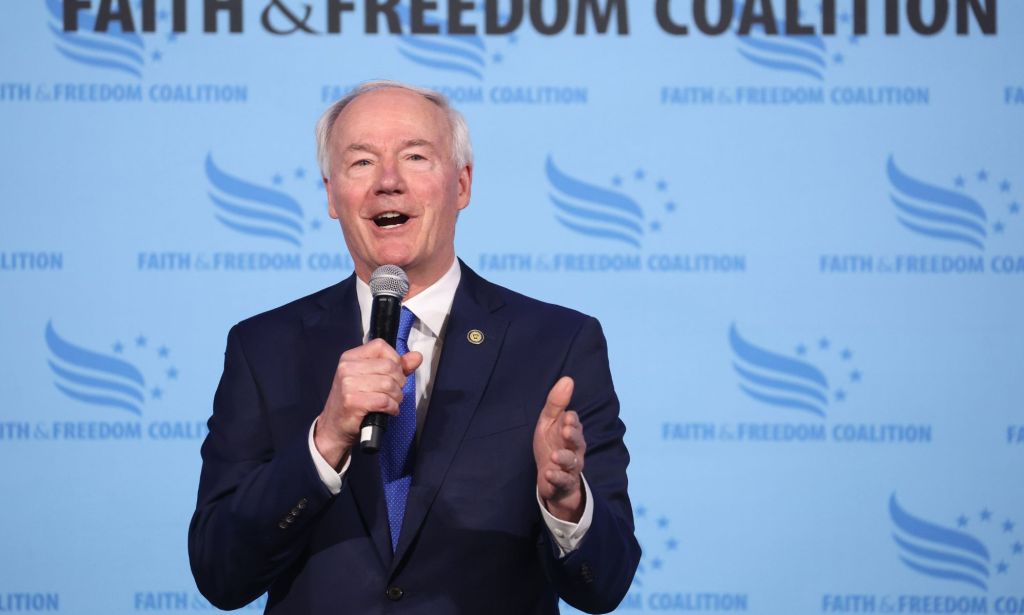 Former Arkansas governor Asa Hutchinson, who is a 2024 Republican presidential candidate, wears a suit and tie as he speaks into a microphone at a conservative religious convention