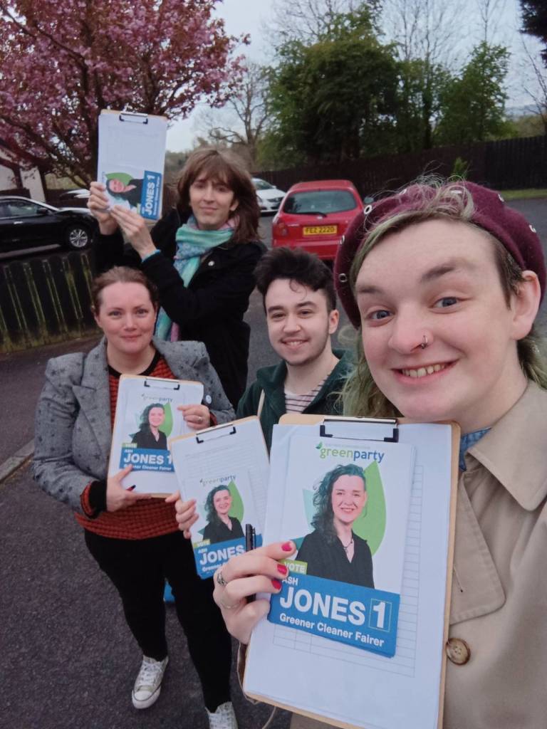Trans activist ash Jones holds up a flyer with her face on it as she runs for a Green Party seat in Northern Ireland