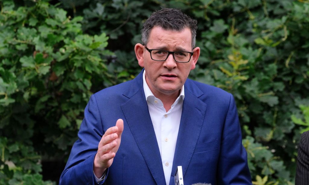 Dan Andrews, premier of the Australian state of Victoria, wears a white shirt and blue jacket as he stands outside and gestures with one hand