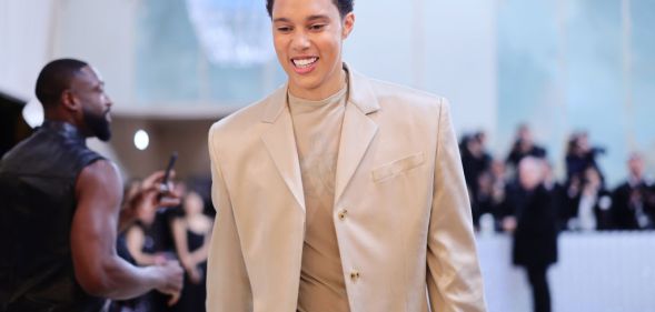 Brittney Griner, a Black woman with short hair, wearing a cream coloured suit on the Met Gala white carpet