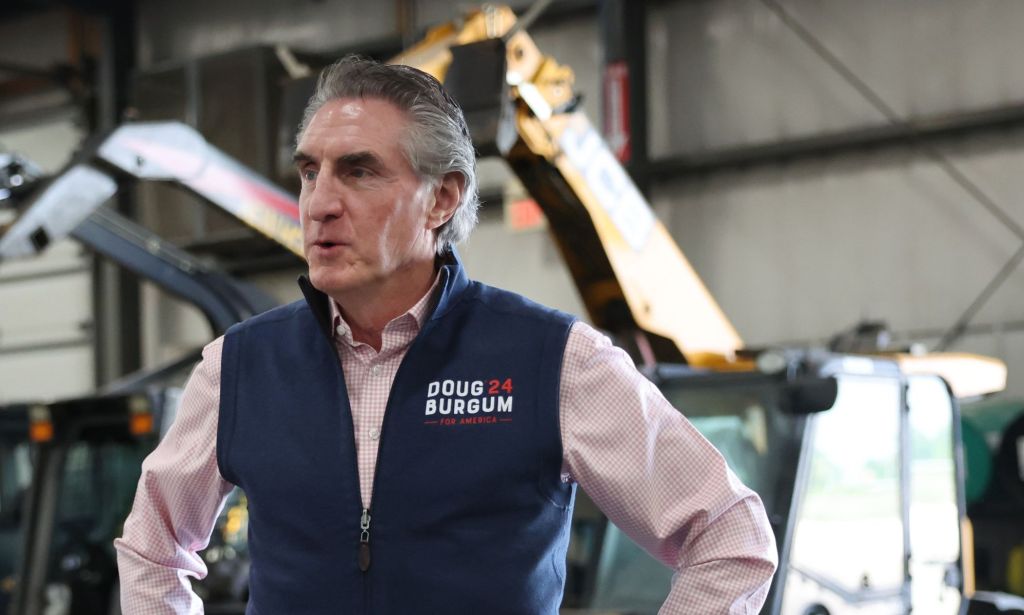 Doug Burgum, who is a 2024 Republican presidential candidate, light red shirt and blue vest as he speaks to someone off camera