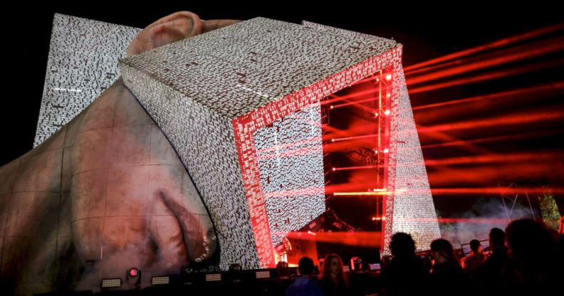 A huge festival stage in the shape of a human head with a cube protruding from it