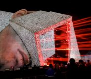 A huge festival stage in the shape of a human head with a cube protruding from it