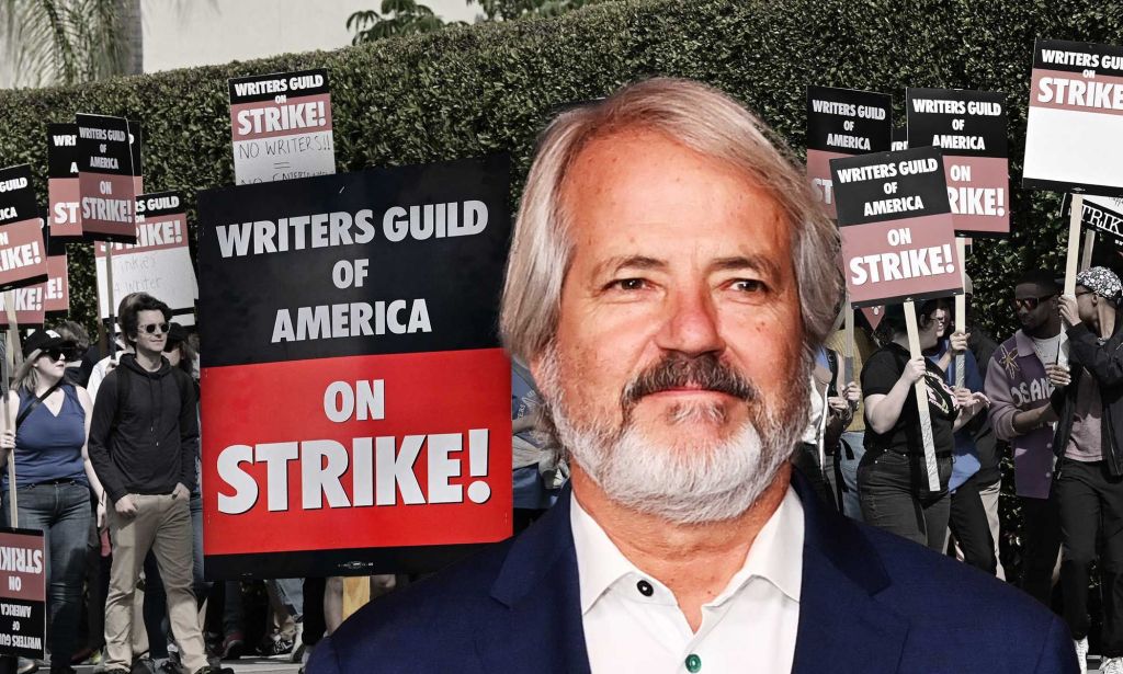Graham Yost, creator of Silo, pictured against the background of a writers' strike protest with a sign saying "writers guild of America on strike!"
