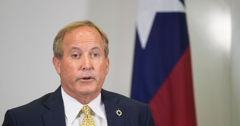 Texas attorney general Ken Paxton, who has repeatedly pushed back on trans rights in the states, speaks to people off camera while wearing a white shirt, yellow tie and dark suit jacket