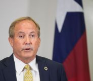 Texas attorney general Ken Paxton, who has repeatedly pushed back on trans rights in the states, speaks to people off camera while wearing a white shirt, yellow tie and dark suit jacket