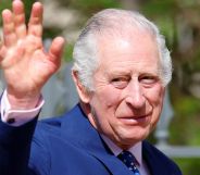King Charles III wears a blue suit as he waves at people gathered outside