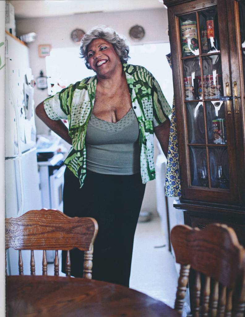Black trans activist Black trans activist Miss Major Griffin-Gracy wears a green printed shirt with a grey top underneath and black trousers as she stands in what appears to be a kitchen and dining room