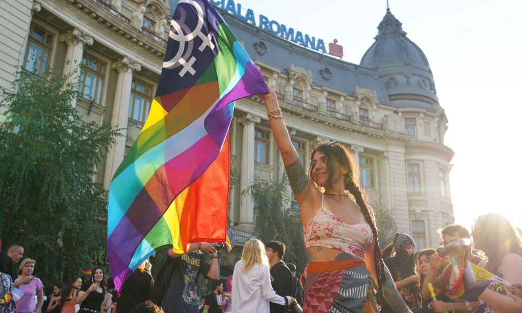A person holds a Pride flag at Bucharest Pride.