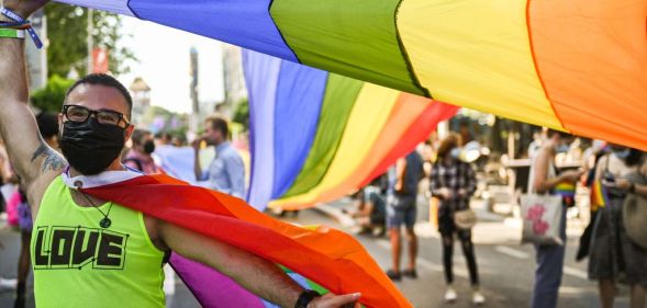 A participant poses with a rainbow flag during the Pride Parade in Bucharest on August 14, 2021.