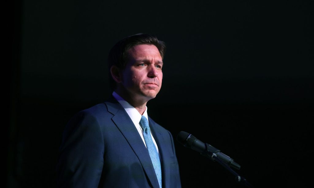 Republican governor Ron DeSantis, who has launched his 2024 presidential campaign, wears a suit and tie as he stands in a dark background