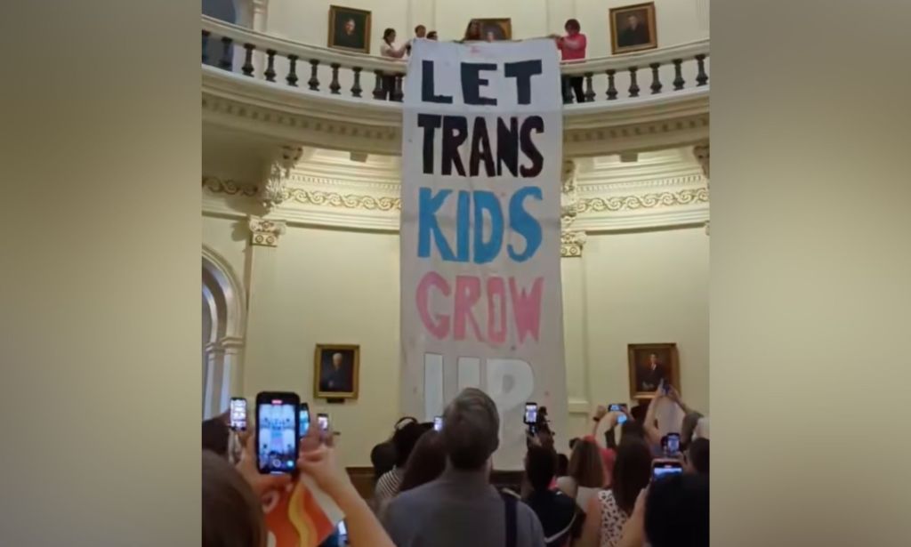LGBTQ+ advocates unfurl a giant banner reading "Let trans kids grow up" in the Texas Capitol rotunda as lawmakers consider a proposed ban on gender-affirming healthcare for trans youth in Texas