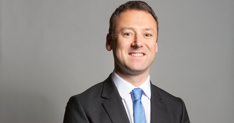 Conservative MP Brendan Clarke-Smith standing in a suit and blue tie against a grey background