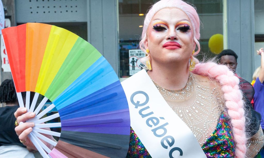 A drag protestor waves a rainbow fan at a Pride event.
