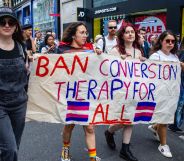 Activists hold a sign reading "ban conversion therapy for all."