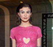 Dylan Mulvaney attends the premiere of LA musical A Transparent Musical wearing a pink dress with a heart cut out and slicked back short brown hair.