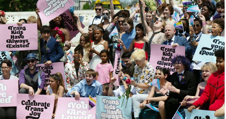 A group of trans youth hold signs of trans solidarity.