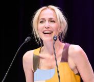 Gillian Anderson in a blue and yellow dress speaking into a microphone.