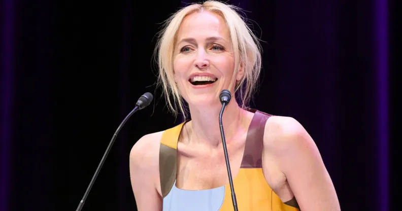Gillian Anderson in a blue and yellow dress speaking into a microphone.