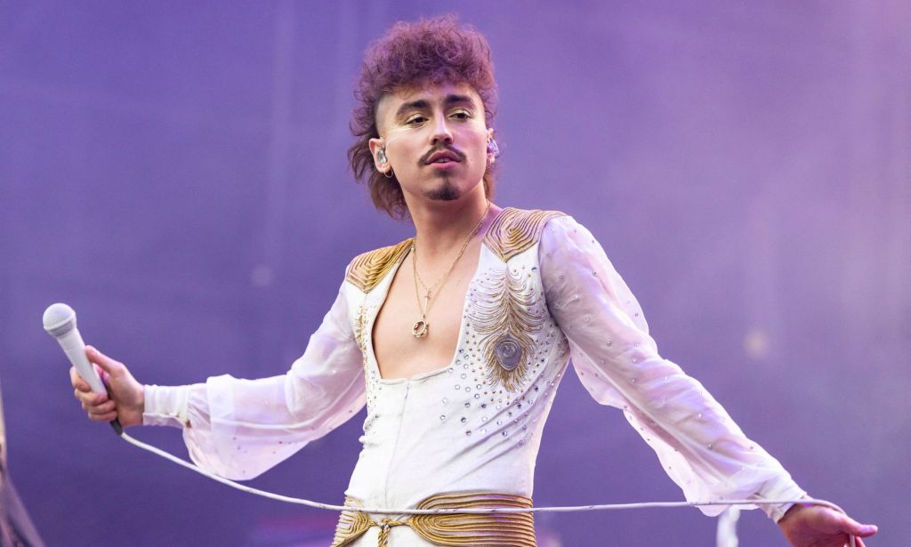Greta Van Fleet's Josh Kiszka performs on stage, holding a microphone.