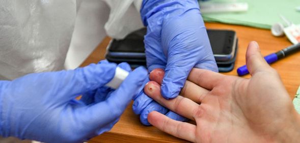 A person gets a finger prick test, often used to identify HIV.