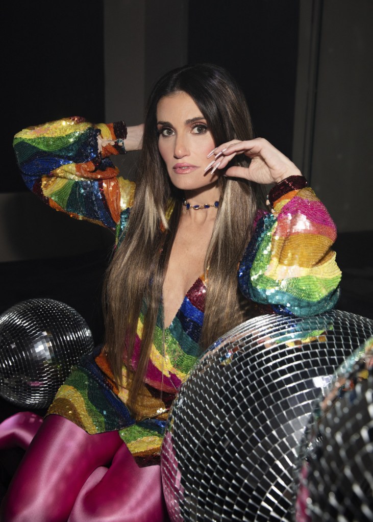 Idina Menzel in a rainbow glitter dress surrounded by disco balls.