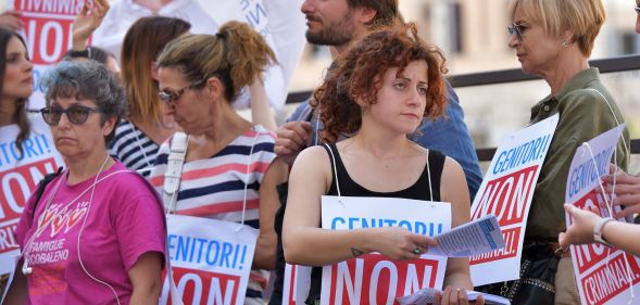 Italian protestors condemning the criminlisation of surrogacy, with signs reading "parents, not criminals."