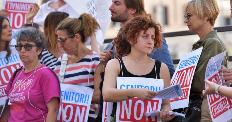 Italian protestors condemning the criminlisation of surrogacy, with signs reading "parents, not criminals."