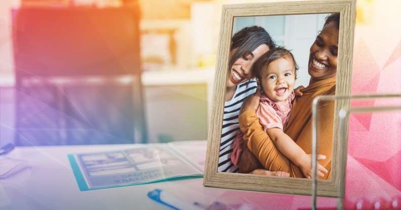 This is an image of an LGBTQ couple with their child in a picture frame. In the background is an office setup that is creatively overlayed with a prism.