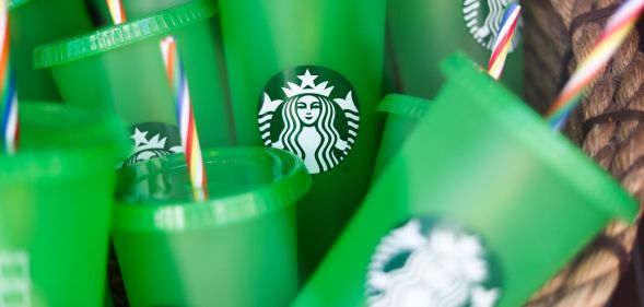 A set of green Starbucks brand cups with red, white, and blue straws in a pile together.