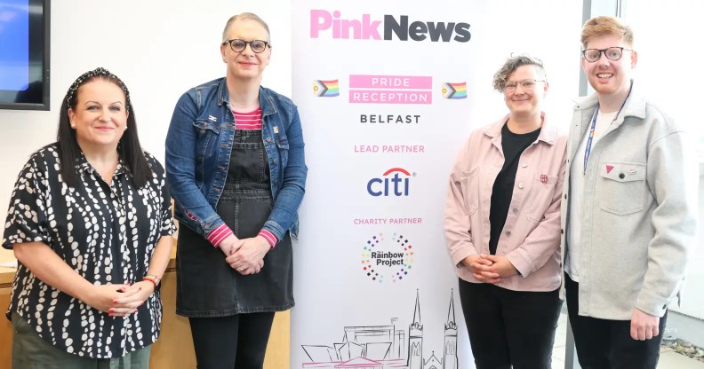 From left to right, Cara McCann, Kirsty Mulholland, Liz Skelcher and Odhrán Devlin at a Citi community lunch which was hosted in partnership with PinkNews. They are standing around a PinkNews banner which advertises the Belfast reception in partnership with Citi.