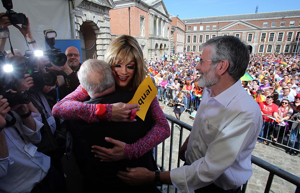 Drag queen and gay rights activist, Rory O'Neill (C) hugs Senator David Norris (L) with Sinn Fein President Gerry Adams looking on at Dublin Castle as they wait for the result of the referendum on May 23, 2015.