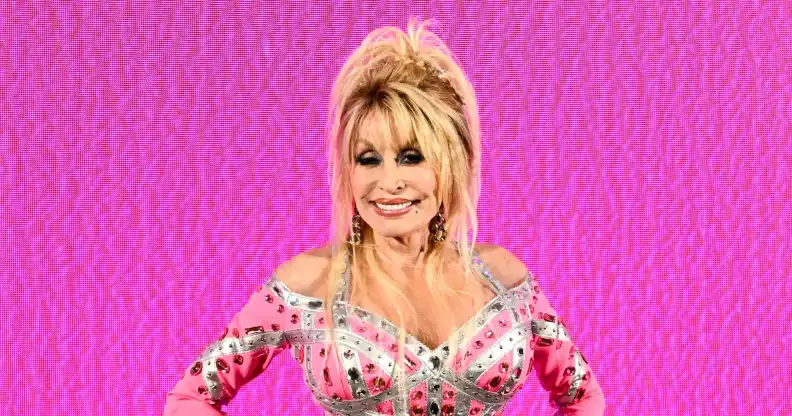 Dolly Parton in a pink patterned dress against a pink background